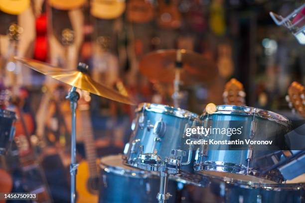 musical instrument shop window. blurred background. drum kit in the foreground - music shop stock pictures, royalty-free photos & images