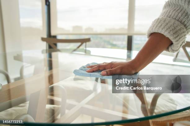 hand of unrecognizable black woman cleaning glass of dining table, day lights at background. - straccio foto e immagini stock