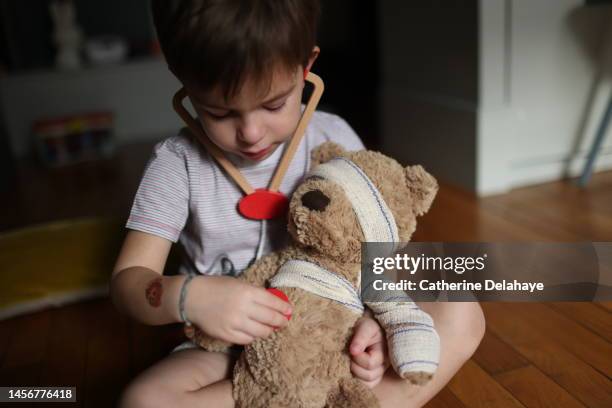 a 4 year old boy playing doctor with his teddy bear in his bedroom - boy exam stock pictures, royalty-free photos & images