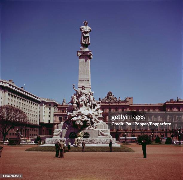 Visitors stand beneath the Monument to Christopher Columbus beside Avenida La Rabida and in front of Casa Rosada in the centre of Buenos Aires,...