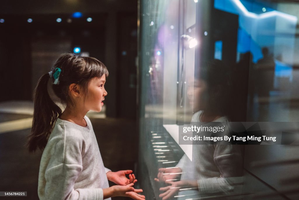 Lovely cheerful girl checking out exhibits in gallery