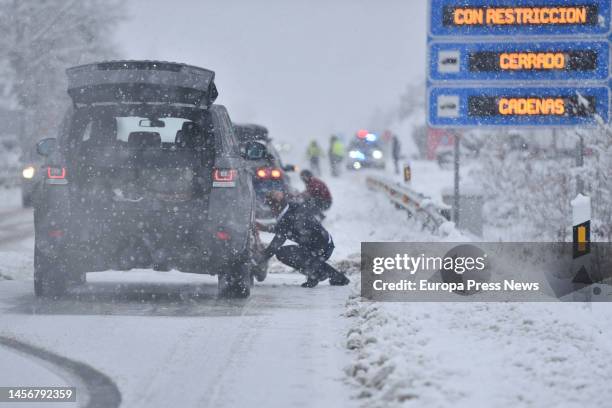 Several people put chains on cars on a snowy road, on 16 January, 2023 in Huesca, Aragon, Spain. The snow that began to fall in the early hours of...