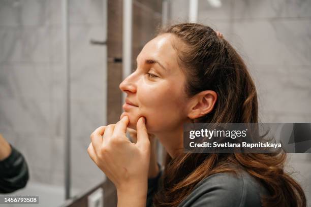 woman doing facial massage with gua sha stone in front of a mirror - massaggio del viso foto e immagini stock