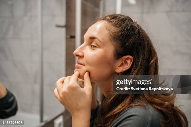 woman doing facial massage with gua sha stone in front of a mirror - bathroom exercise stock pictures, royalty-free photos & images