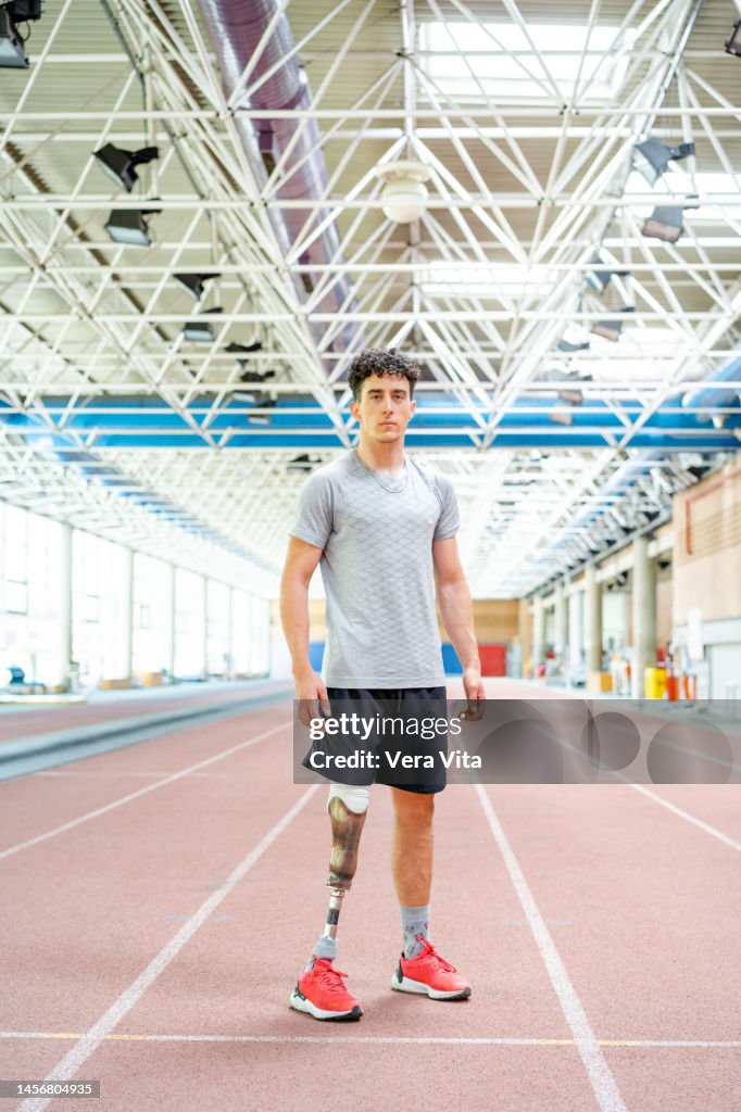 Panoramic view of caucasian male runner with leg prosthesis standing at stadium indoors