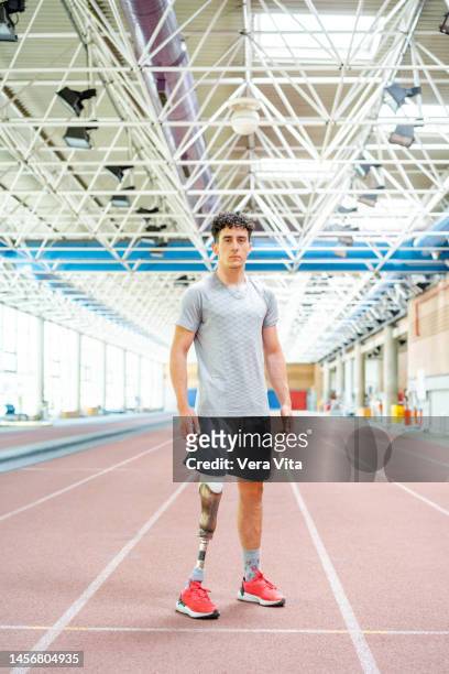 panoramic view of caucasian male runner with leg prosthesis standing at stadium indoors - amputee running stock pictures, royalty-free photos & images