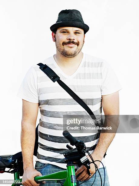 Man wearing hat holding bicycle smiling