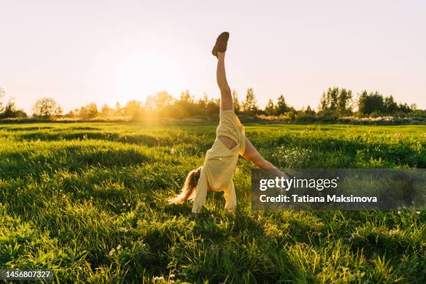 a teenage girl with curly hair dance in a field at sunset. - flickor bildbanksfoton och bilder