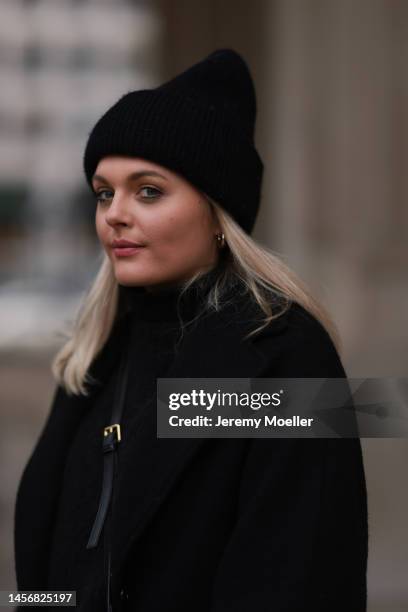 Sarah wearing a black long coat, black Aylin Koenig turtleneck sweater, Mango black crossbody bag and a black Zara knit hat on January 12, 2023 in...