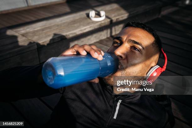 man drinking sport hydration drink from bottle - energydrink stock-fotos und bilder