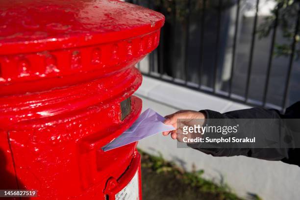 british red postal box with with a letter being deposited in. london uk - democracy uk stock pictures, royalty-free photos & images