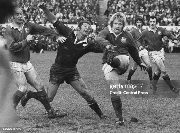 Steve Fenwick, Centre for the British and Irish Lions kicks the ball up field as Kevin Eveleigh, flanker for the New Zealand All Blacks attempts to...
