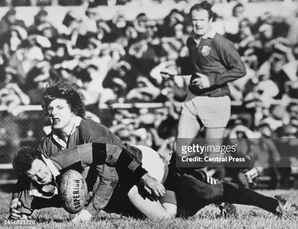 Alan McLellan, prop for the Canterbury Rugby Football team is tackled to the ground by Fergus Slattery, flanker for the British and Irish Lions...