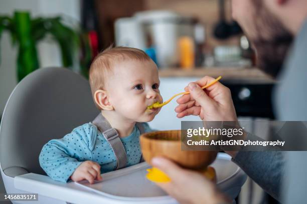Caring single father spoon feeding his beautiful son.