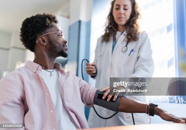 portrait of a man receiving medical care while smiling - bloeddrukmeter stockfoto's en -beelden