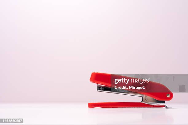 red stapler on pink background - tacler stock-fotos und bilder