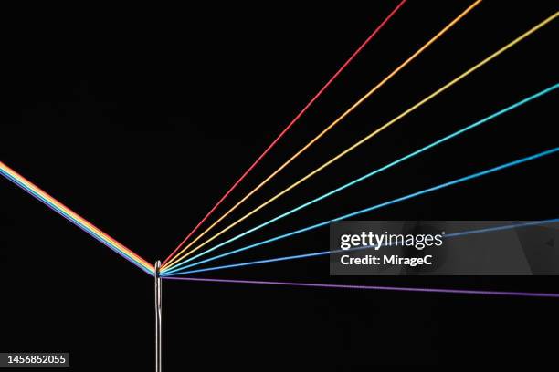 rainbow refraction by color threads through needle eyelet - nadel kurzwaren stock-fotos und bilder