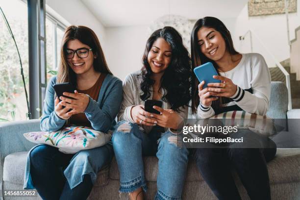 three friends using mobile phones together at home - venezolanskt ursprung bildbanksfoton och bilder