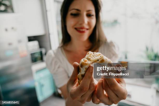 joven adulta mostrando el interior de una empanada a la cámara - empanada fotografías e imágenes de stock