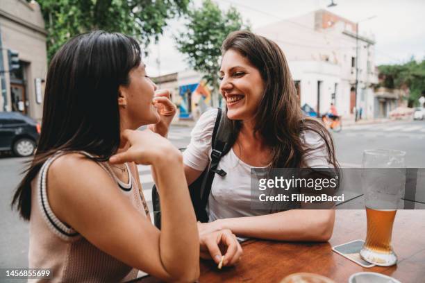 zwei freundinnen sitzen in einem café und trinken bier und cocktails - eating nuts stock-fotos und bilder