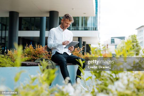 geschäftsmann im finanzviertel mit digitalem tablet - center stock-fotos und bilder