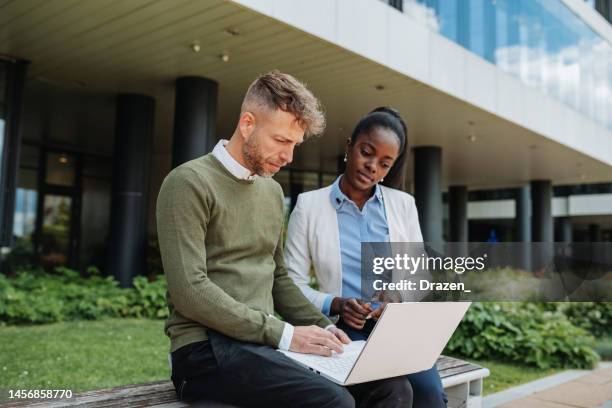 geschäftsleute im finanzdistrikt, diverse kollegen, die in der nähe von green building arbeiten und technologien nutzen - arbeiten outdoor stadt laptop stock-fotos und bilder