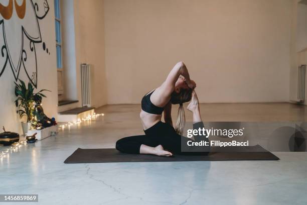 young woman practicing yoga in one legged king pigeon pose - yogi stock pictures, royalty-free photos & images