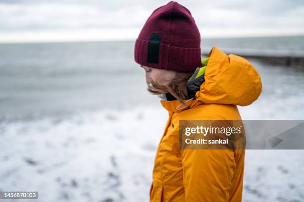 woman stands alone at the coastline of the sea - winter sadness stock pictures, royalty-free photos & images