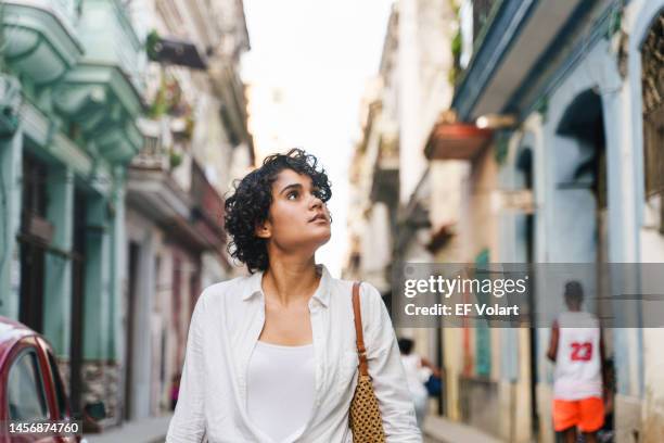 young hispanic woman walking down street in havana city - havana stockfoto's en -beelden