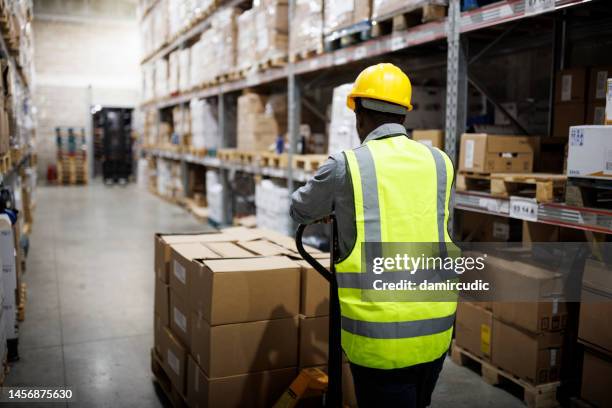 arbeiter zieht einen hand-lkw im lager - arbeitsmarkt stock-fotos und bilder