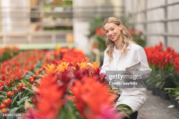 woman with white lab coat working in plant flower shop. - botanist stock pictures, royalty-free photos & images