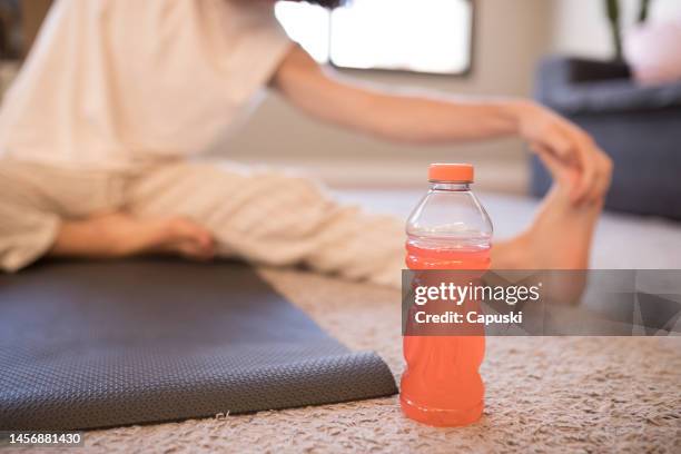 man doing yoga with an isotonic drink next to him - sport drink stock pictures, royalty-free photos & images