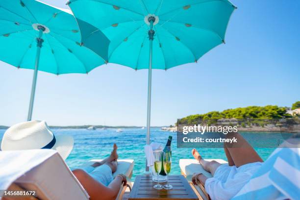 zwei frauen entspannen am strand mit champagner. - liegestuhl stock-fotos und bilder