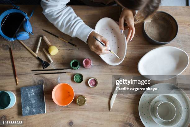 skillful young woman in apron painting pottery at workshop - art and craft stock pictures, royalty-free photos & images