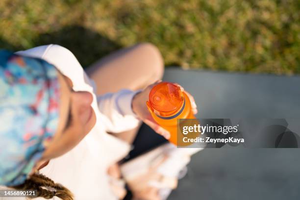 young woman hydrating with a bottle of sports drink - drinking from bottle stock pictures, royalty-free photos & images