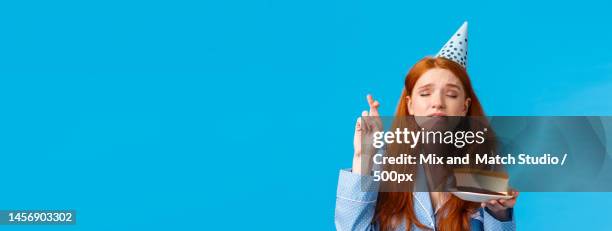 young woman blowing party horn blower against blue background - party horn blower bildbanksfoton och bilder