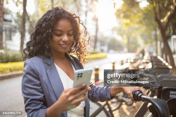 young woman using mobile phone to rent a bike - bicycle rental stockfoto's en -beelden