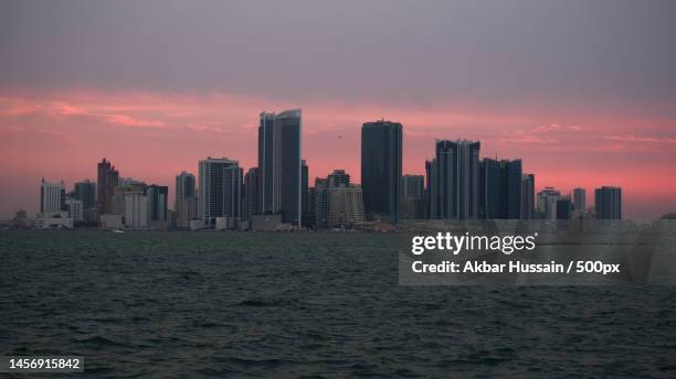 scenic view of sea and buildings against sky during sunset,bahrain - bahrain business stock pictures, royalty-free photos & images