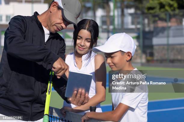 trainer, der seinen schülern tennisstrategien mit einem tablet zeigt - gruppe springen ipad stock-fotos und bilder