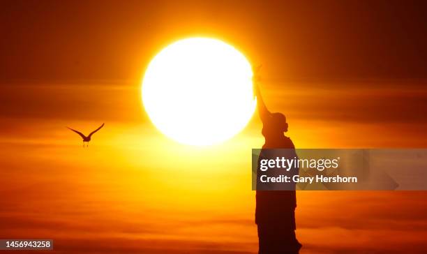 The sun sets behind the Statue of Liberty on January 16 in New York City.