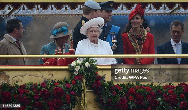 Queen Elizabeth II stands in front of Prince Harry, Prince William, Duke of Cambridge and Catherine, Duchess of Cambridge on the royal barge 'Spirit...