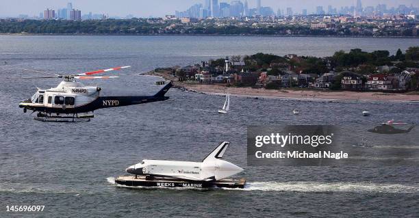 Helicopters fly above Space Shuttle Enterprise, as it's carried by barge past Coney Island, on June 03, 2012 in New York City. Enterprise is on it's...