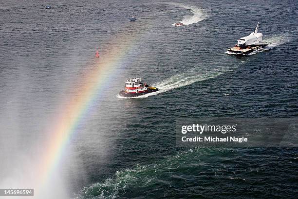 Space Shuttle Enterprise is carried by barge behind a rainbow appearing in the mist sprayed by an FDNY fireboat on June 03, 2012 in New York City....