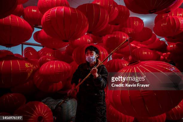 Worker uses a stick to hang red lanterns in a factory on January 5, 2023 in the village of Tuntou, Hebei province, China. The village of Tuntou which...