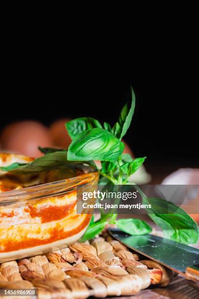 close up of basil leaves with lasagna plate - hartkäse stock-fotos und bilder