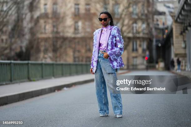 Emilie Joseph @in_fashionwetrust wears black sunglasses, fringed rhinestones long earrings, a purple large sequins halter neck / tank-top, a matching...