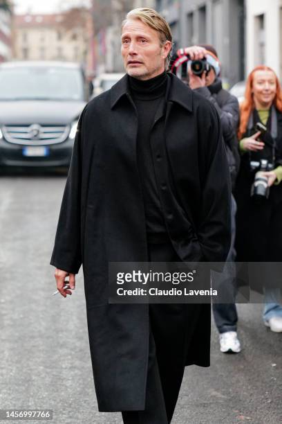 Mads Mikkelsen is seen wearing black loang coat, turtle neck sweater, shirt and suit pants outside the Ermenegildo Zegna show during the Milan...