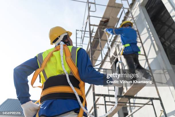 two workers working at height and safety harness at construction site - building site accidents photos et images de collection