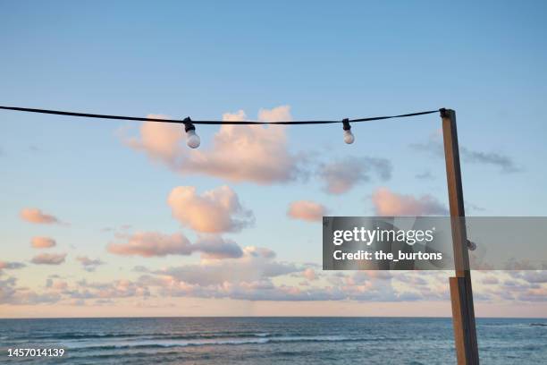 string lights against sea and sky during sunset - lightbulbs in a row stock pictures, royalty-free photos & images