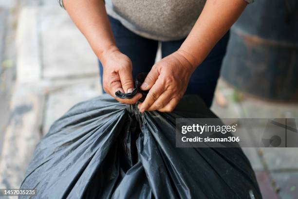 selective focus hands try to tie a trash bag for recycle - sac poubelle photos et images de collection